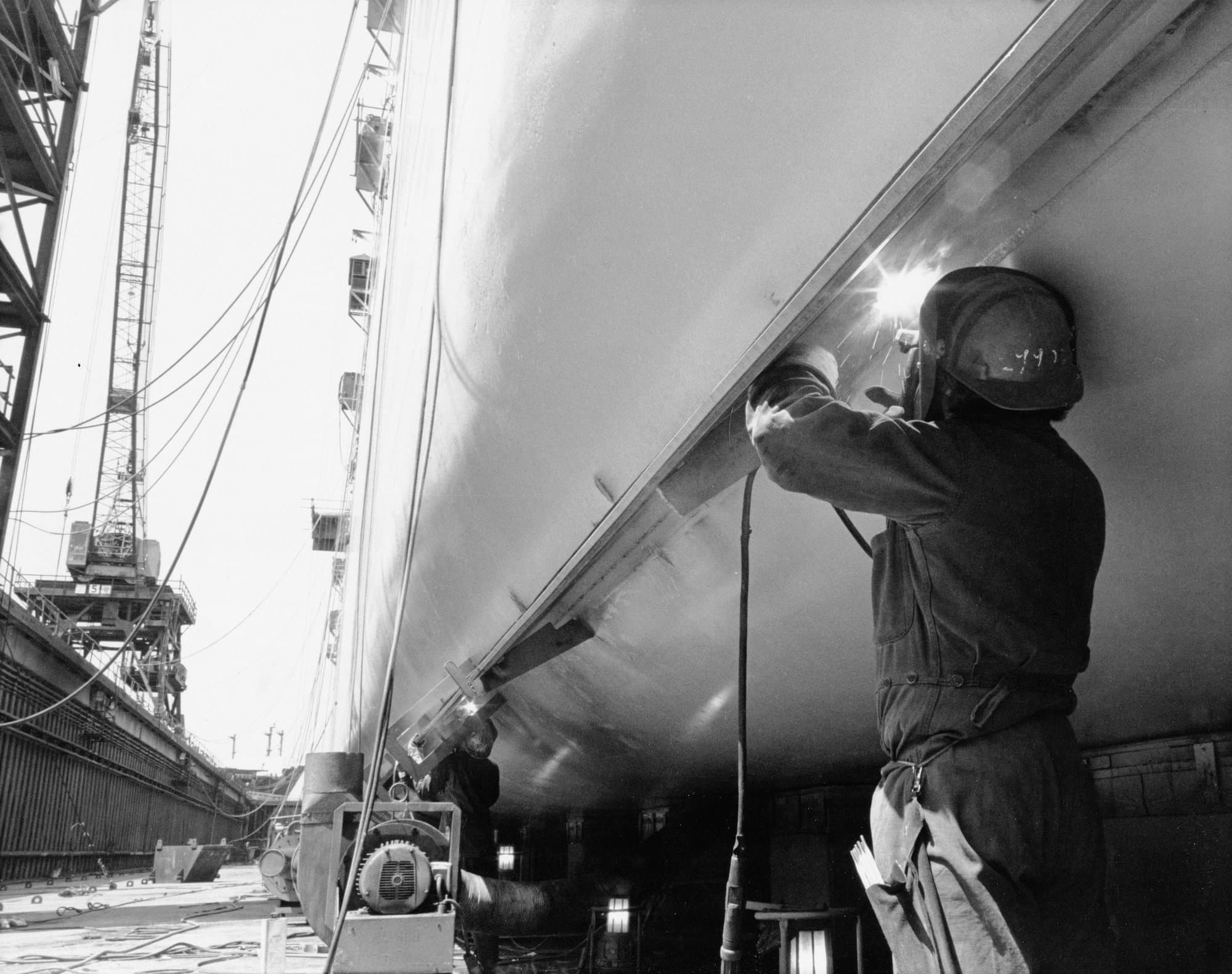 Welder working on a yacht hull in dry dock