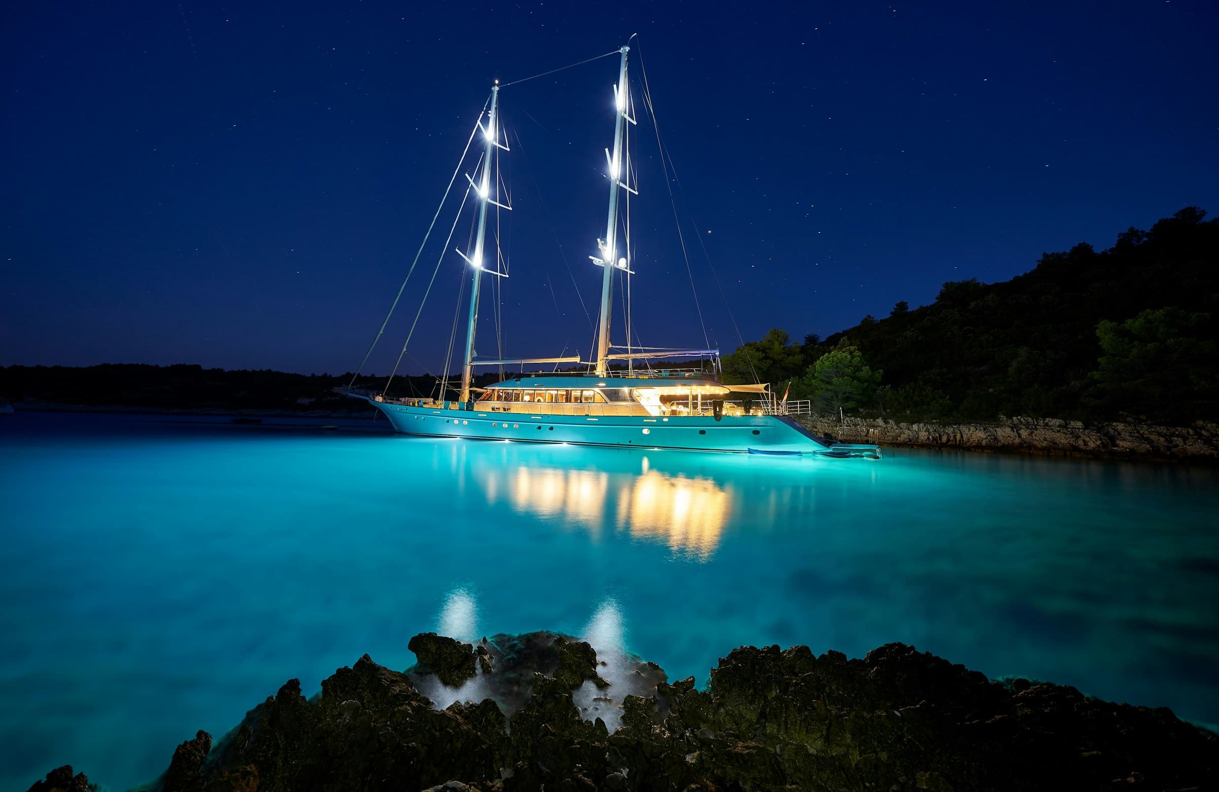 Sailing yacht at anchor in a moonlit cove